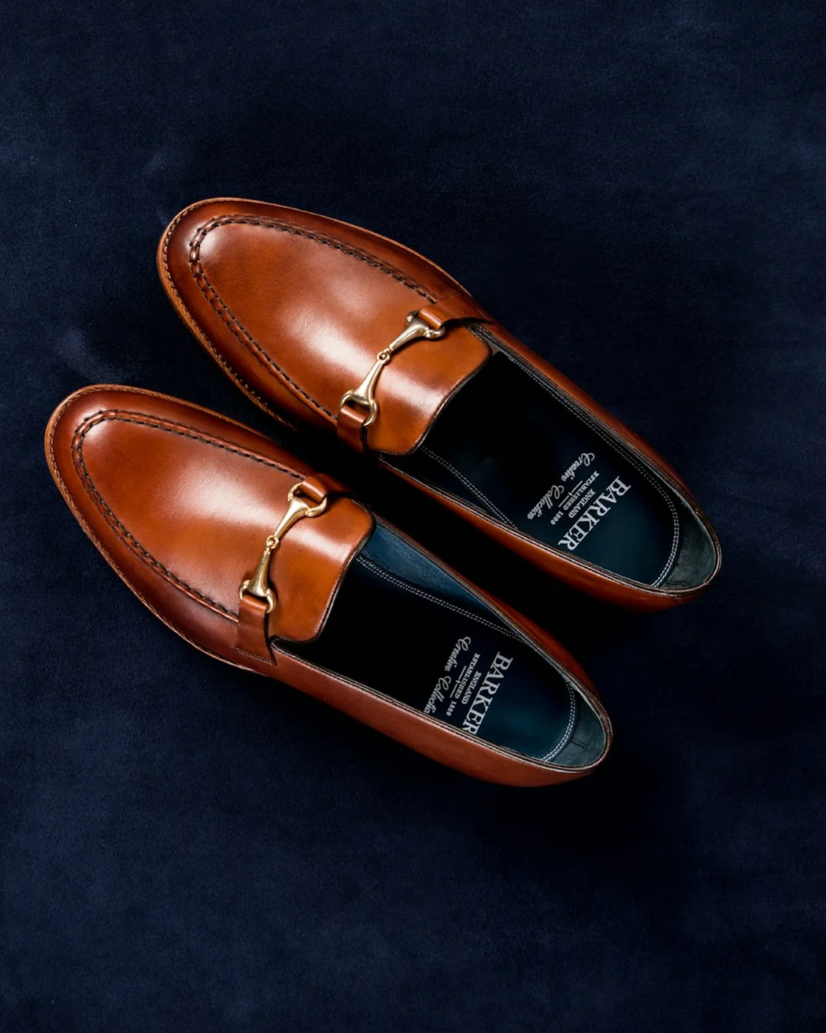 Brown leather loafers photographed on dark fabric